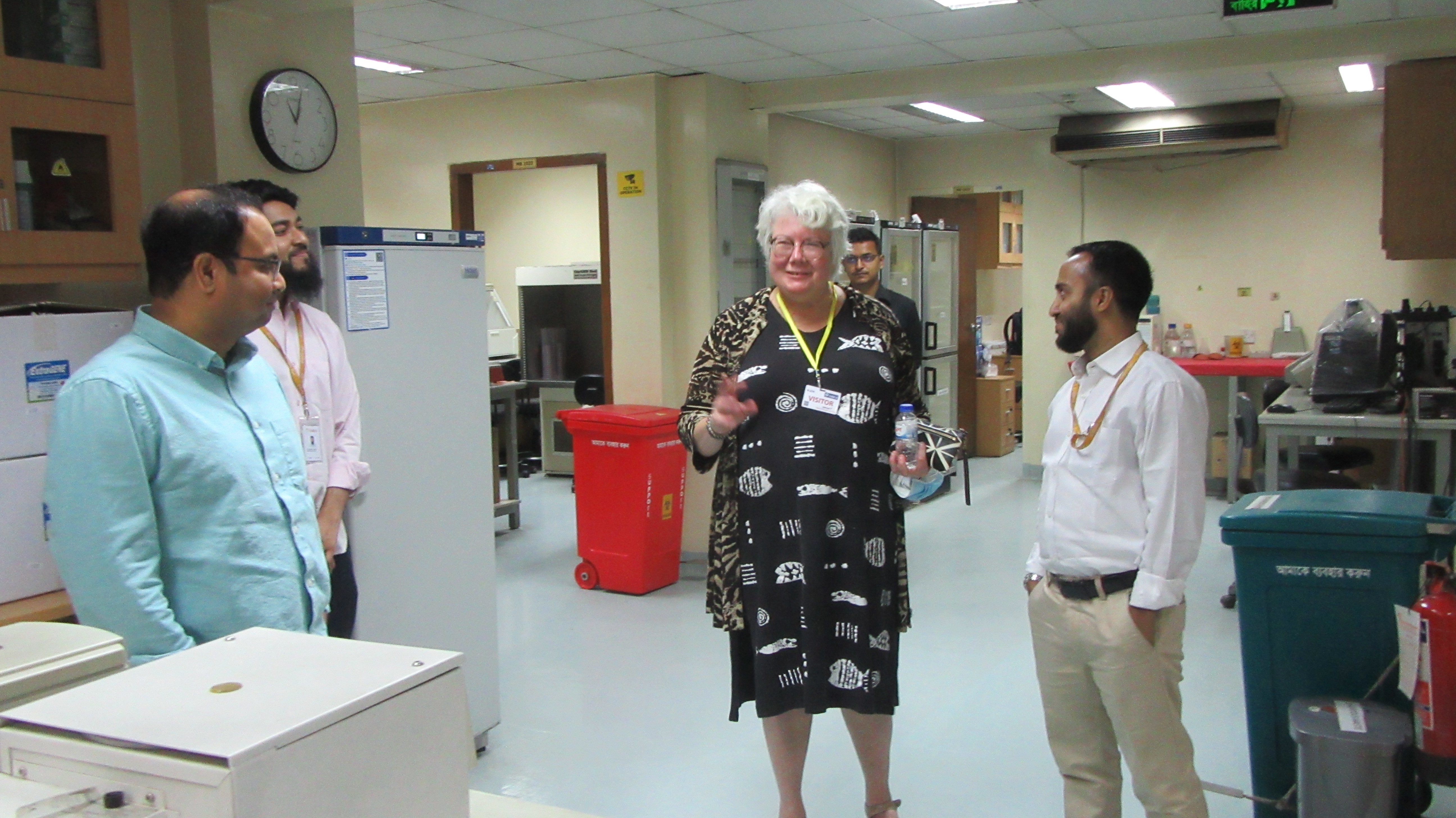 Dr. Clare Narrod meets with researchers in a lab in Bangladesh.