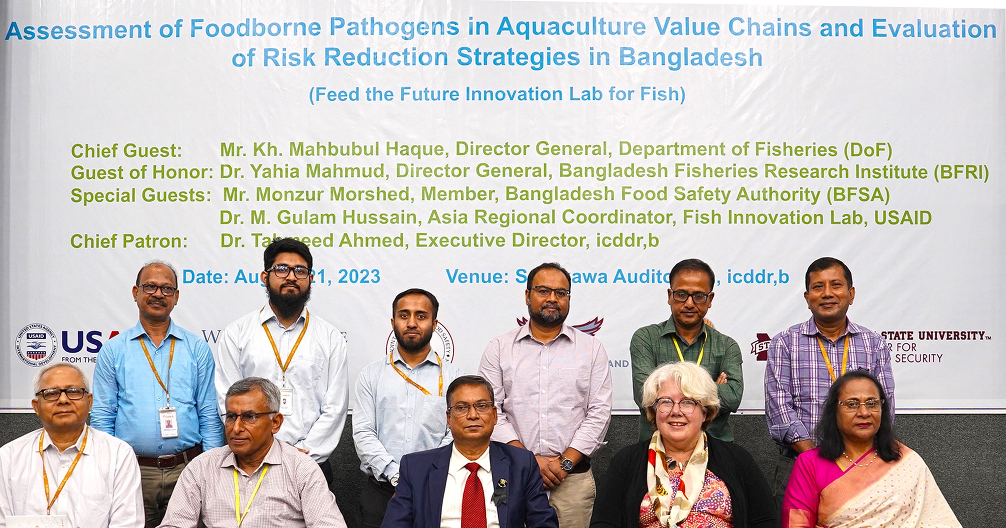 Group photo of scientists and officials in front of the seminar poster.